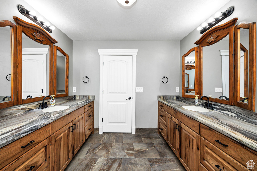 Full bathroom featuring stone finish flooring, two vanities, and a sink