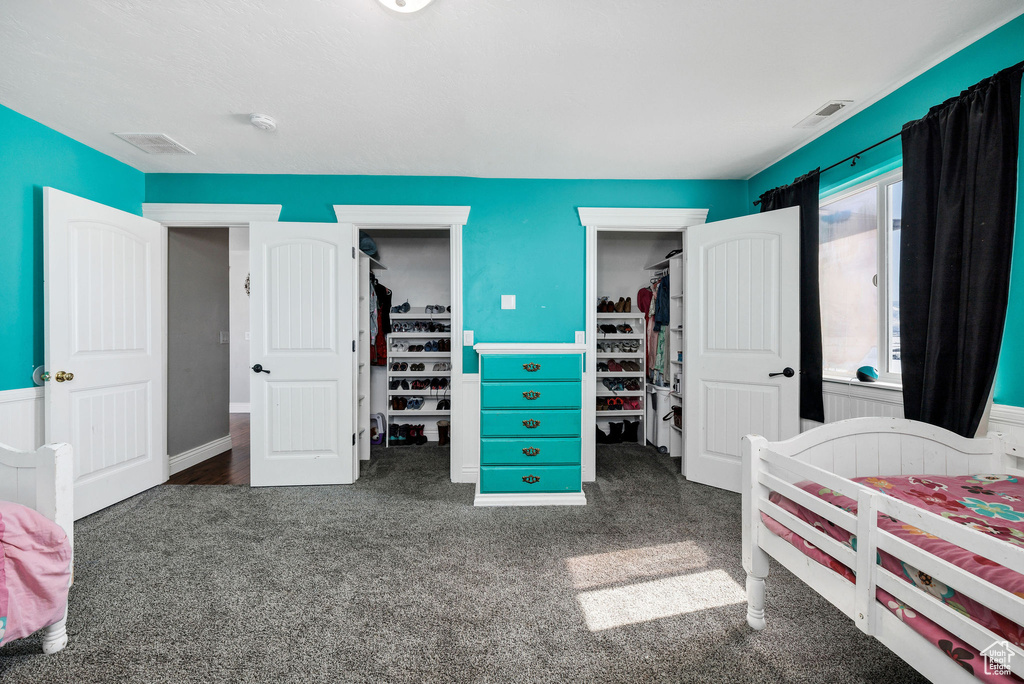 Carpeted bedroom featuring a spacious closet, visible vents, and a closet