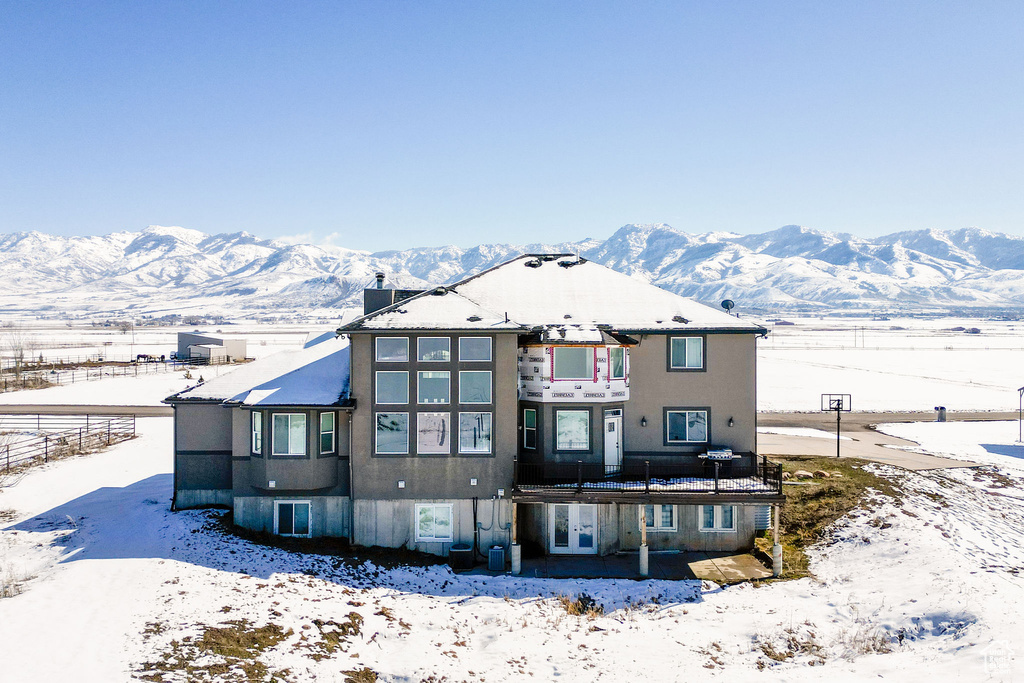 Snow covered house with french doors, a mountain view, and stucco siding