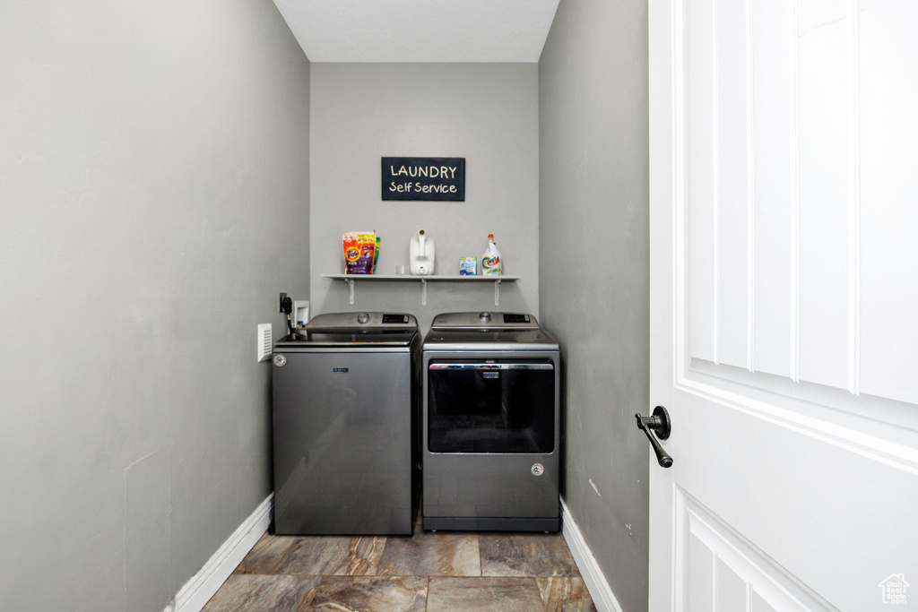 Washroom featuring laundry area, baseboards, and washing machine and clothes dryer