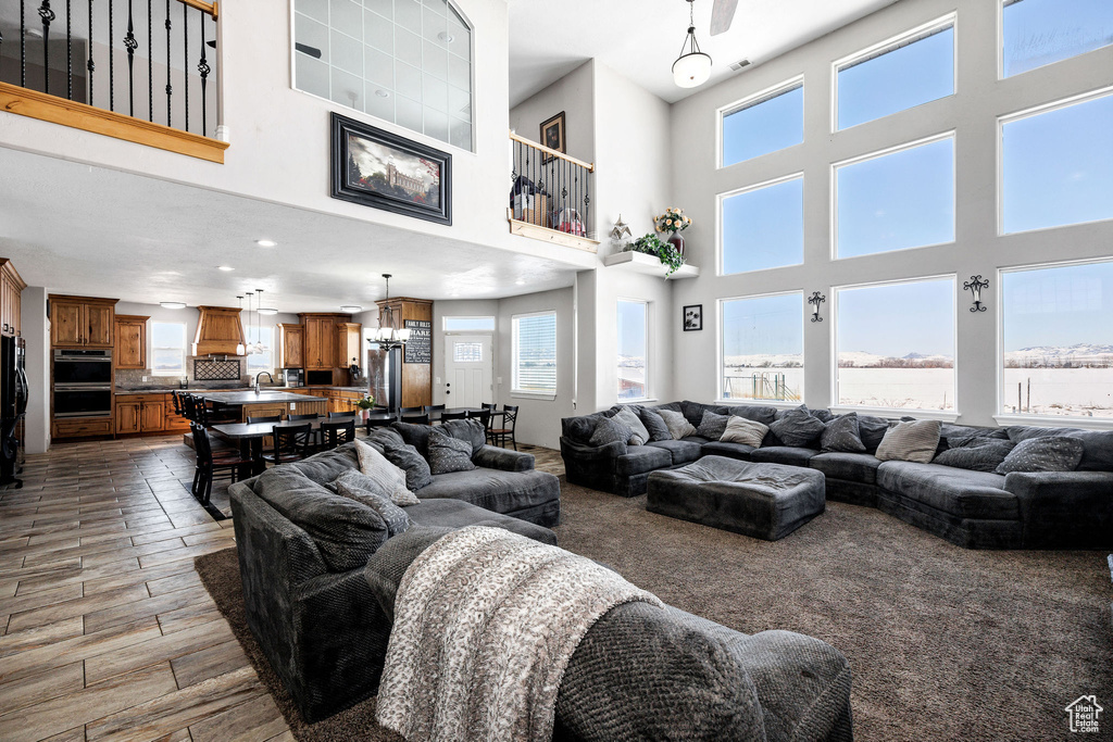 Living room with a chandelier, a towering ceiling, and wood finished floors