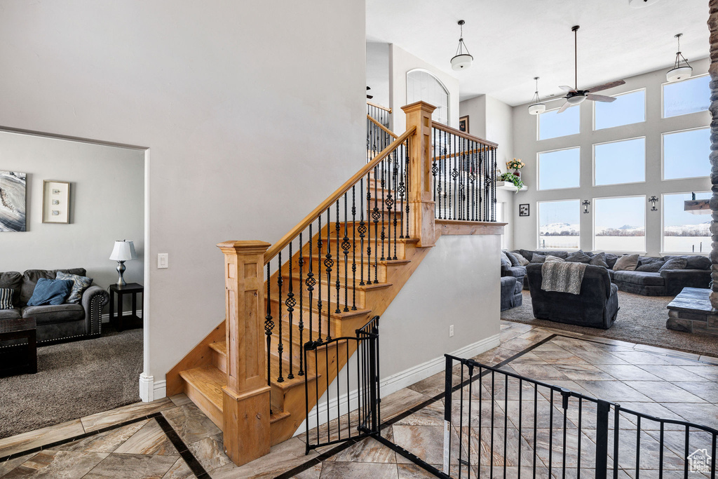 Stairs with marble finish floor, a high ceiling, baseboards, and ceiling fan