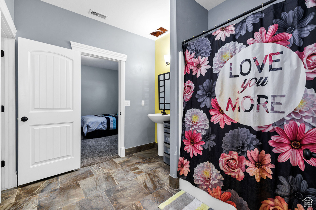 Interior space with a shower with shower curtain, visible vents, baseboards, and stone finish flooring