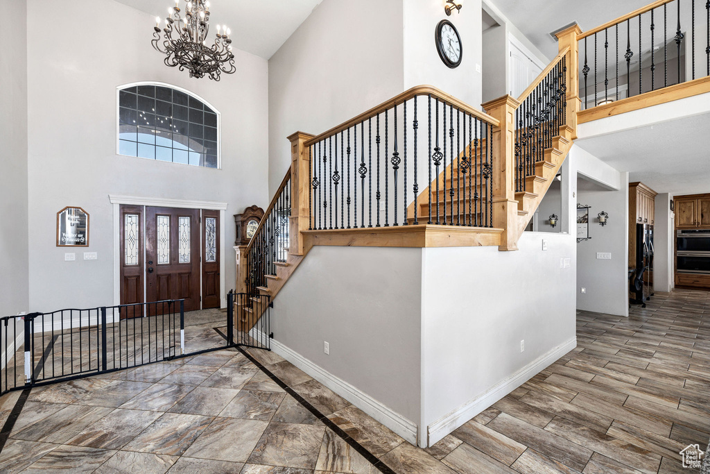 Foyer featuring baseboards, stairway, a high ceiling, an inviting chandelier, and wood finished floors