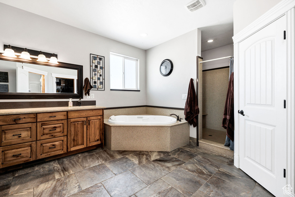 Full bathroom with visible vents, a shower stall, a bath, and vanity