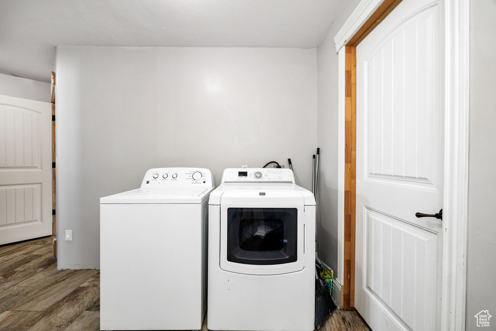 Washroom featuring wood finished floors, washing machine and dryer, and laundry area