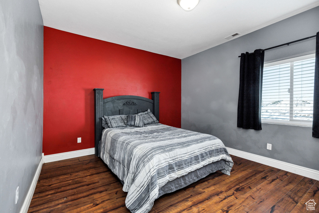 Bedroom with visible vents, baseboards, wood finished floors, and an accent wall