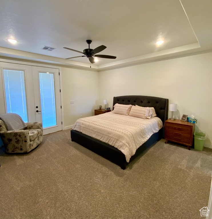 Bedroom featuring carpet, visible vents, a tray ceiling, ceiling fan, and french doors