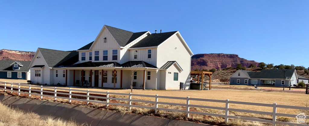 View of front of house featuring a standing seam roof, a mountain view, a fenced front yard, board and batten siding, and metal roof