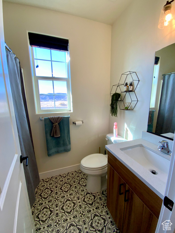 Full bathroom with vanity, tile patterned floors, toilet, and baseboards