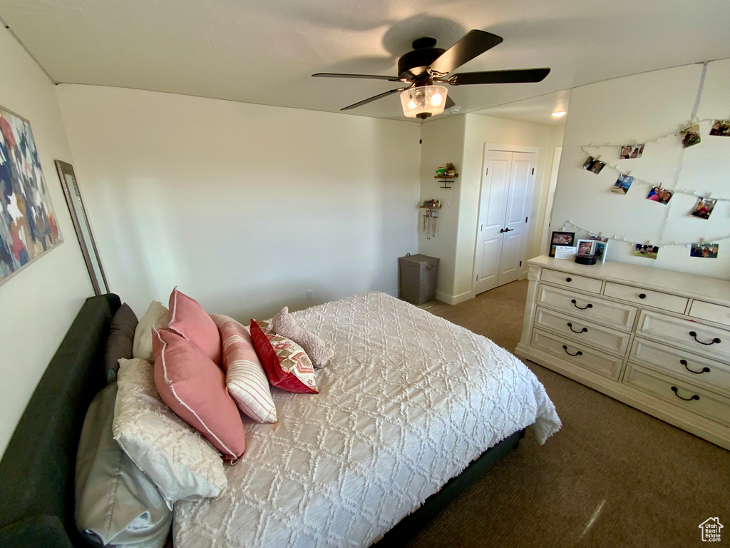 Carpeted bedroom featuring a ceiling fan and a closet