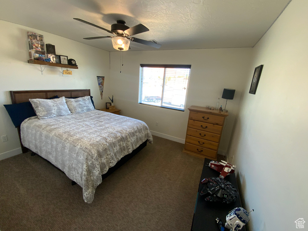 Bedroom with dark colored carpet, baseboards, and a ceiling fan