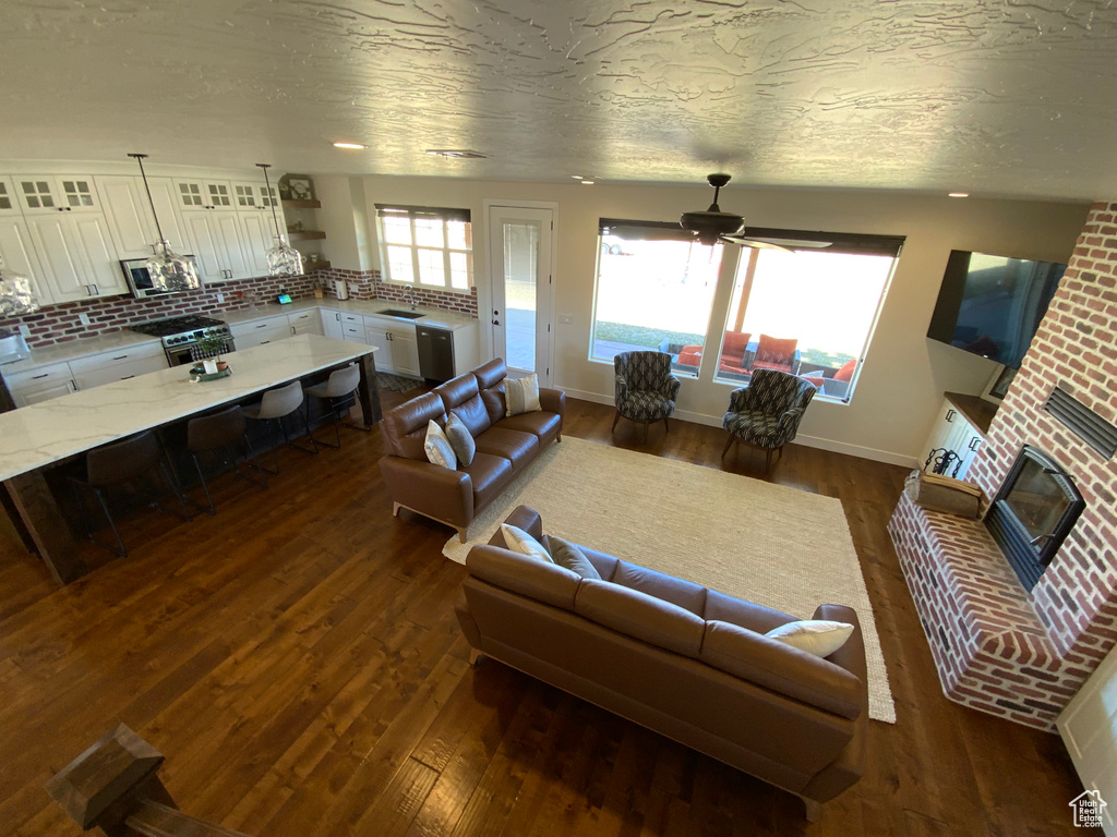 Living area featuring dark wood-type flooring, a fireplace, baseboards, and a textured ceiling