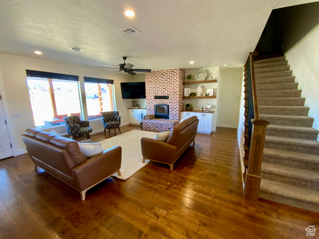 Living room featuring visible vents, dark wood-type flooring, a textured ceiling, stairway, and ceiling fan