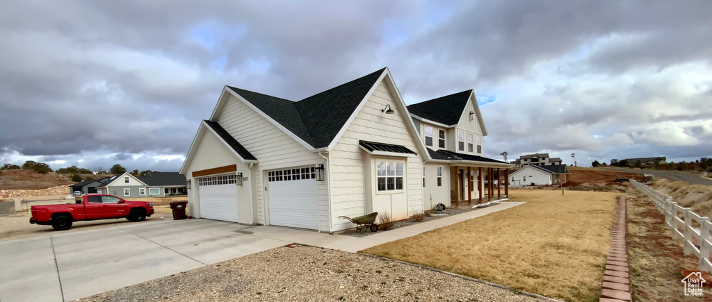 View of side of home featuring an attached garage, driveway, and a shingled roof