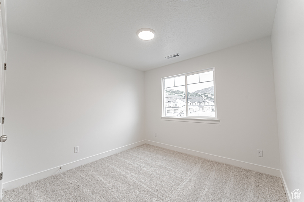 Carpeted spare room with baseboards