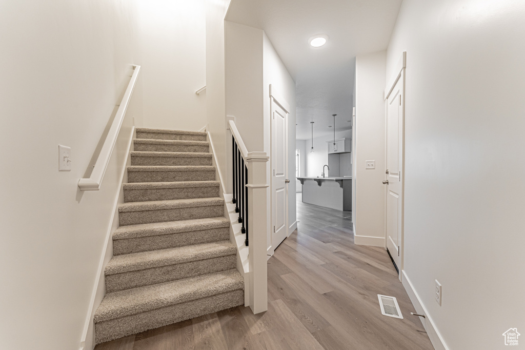 Stairway with wood finished floors and recessed lighting