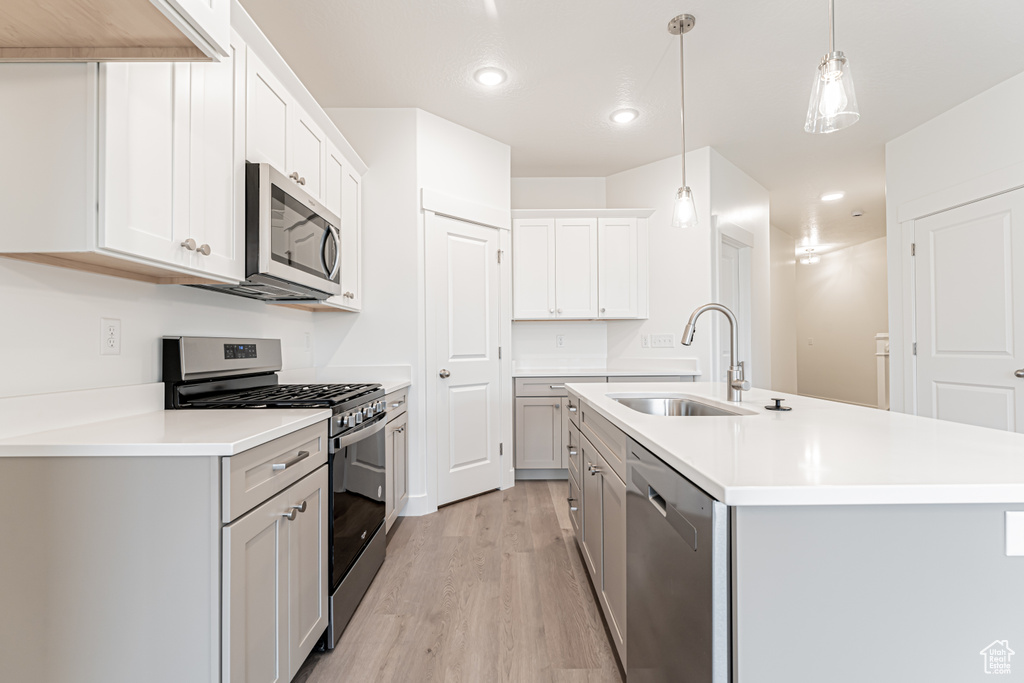 Kitchen with stainless steel appliances, light wood-type flooring, recessed lighting, light countertops, and pendant lighting