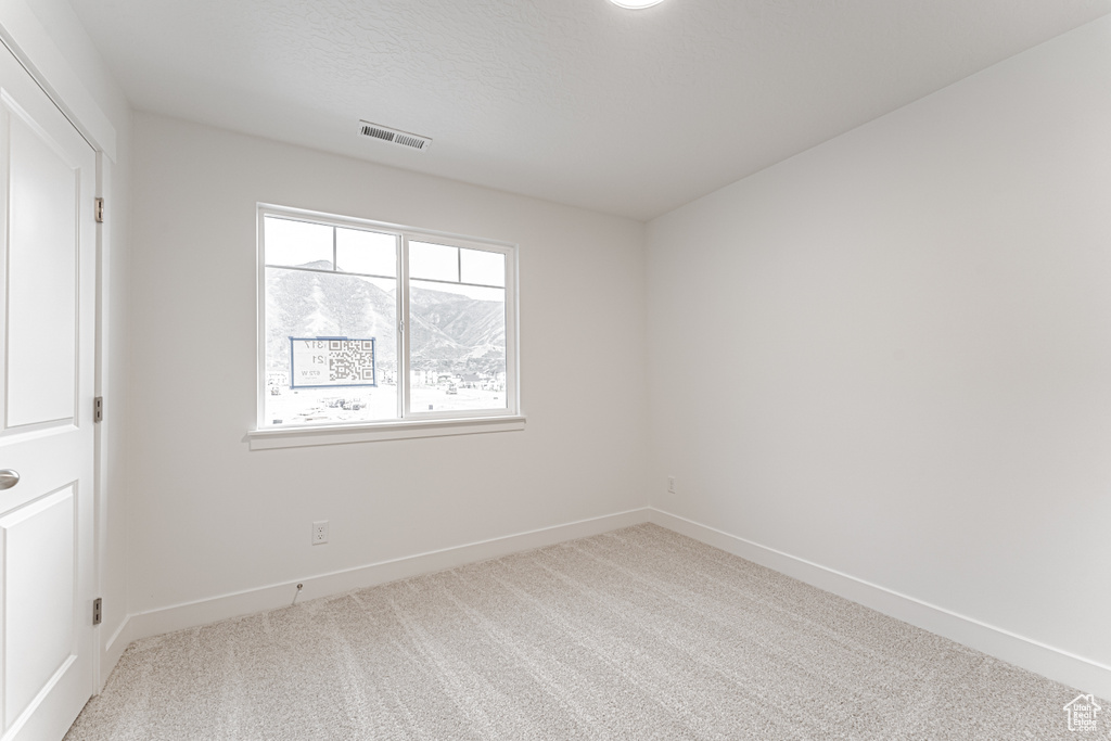 Carpeted spare room featuring baseboards
