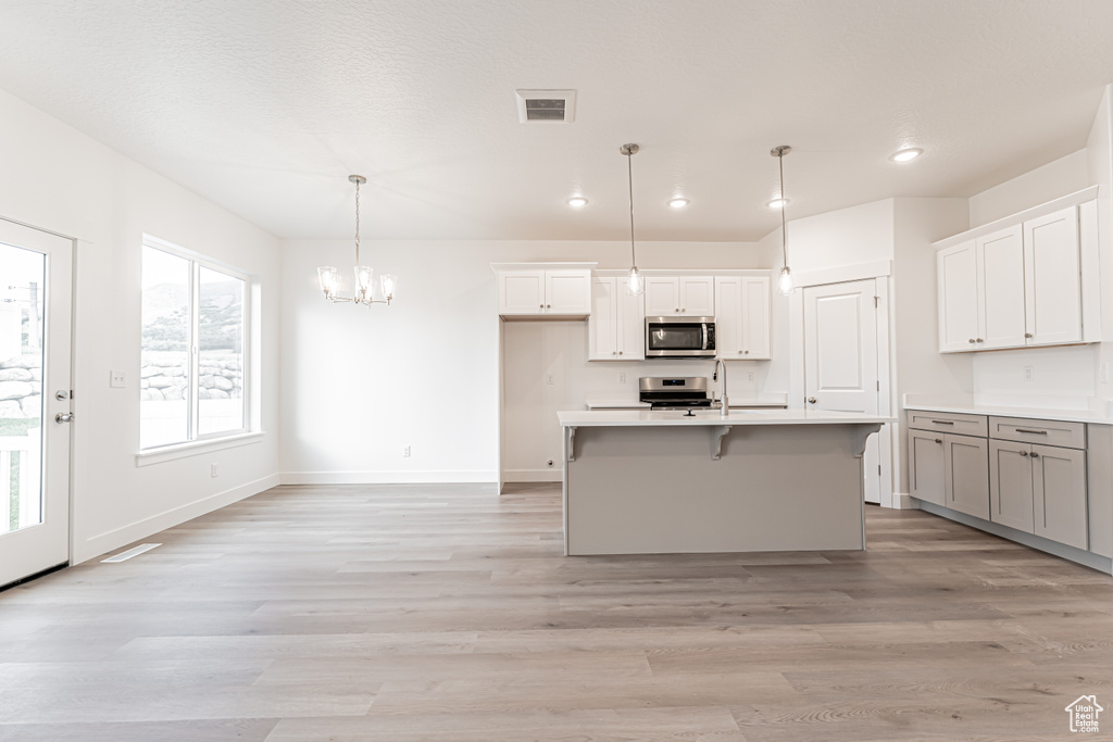 Kitchen featuring stainless steel appliances, a chandelier, light wood-type flooring, recessed lighting, and light countertops