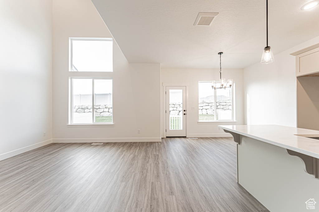 Kitchen with a kitchen breakfast bar, light wood-style flooring, a chandelier, pendant lighting, and light countertops