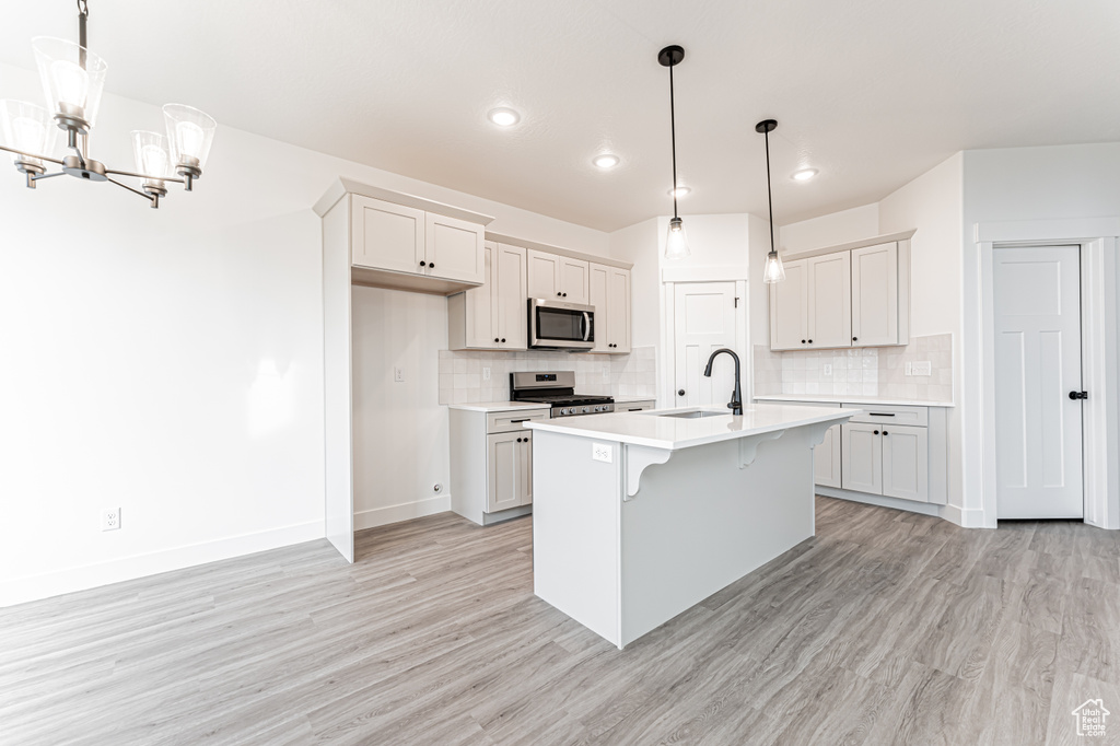 Kitchen featuring stainless steel appliances, a chandelier, light countertops, light wood finished floors, and recessed lighting