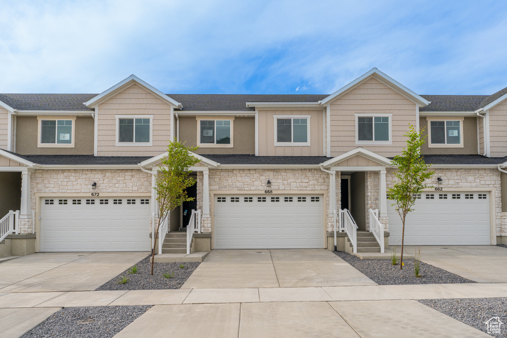 Multi unit property featuring stone siding, a garage, concrete driveway, and board and batten siding