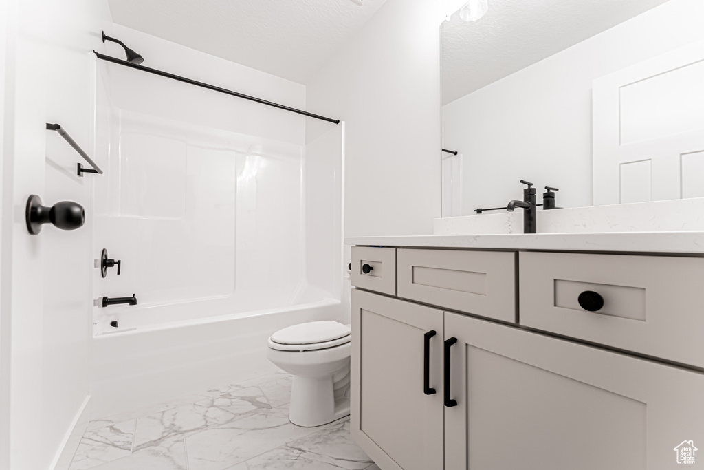 Bathroom with marble look tiles, vanity, and  shower combination