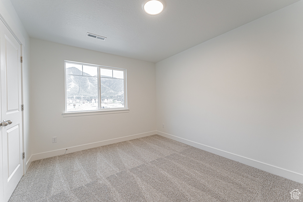 Unfurnished bedroom with light carpet and baseboards