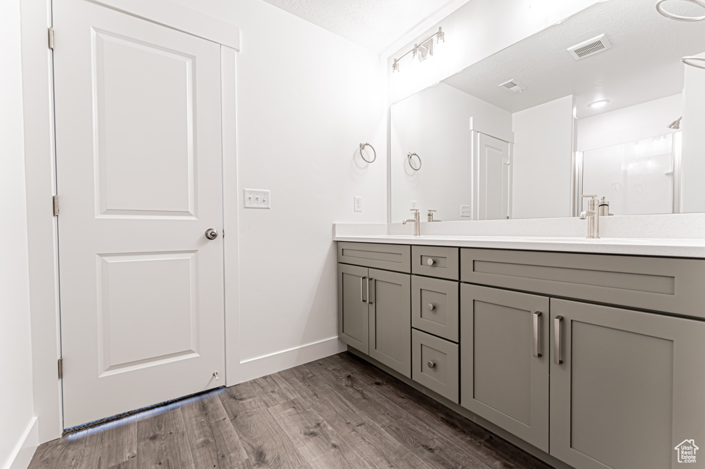 Full bath with double vanity, wood finished floors, and an enclosed shower