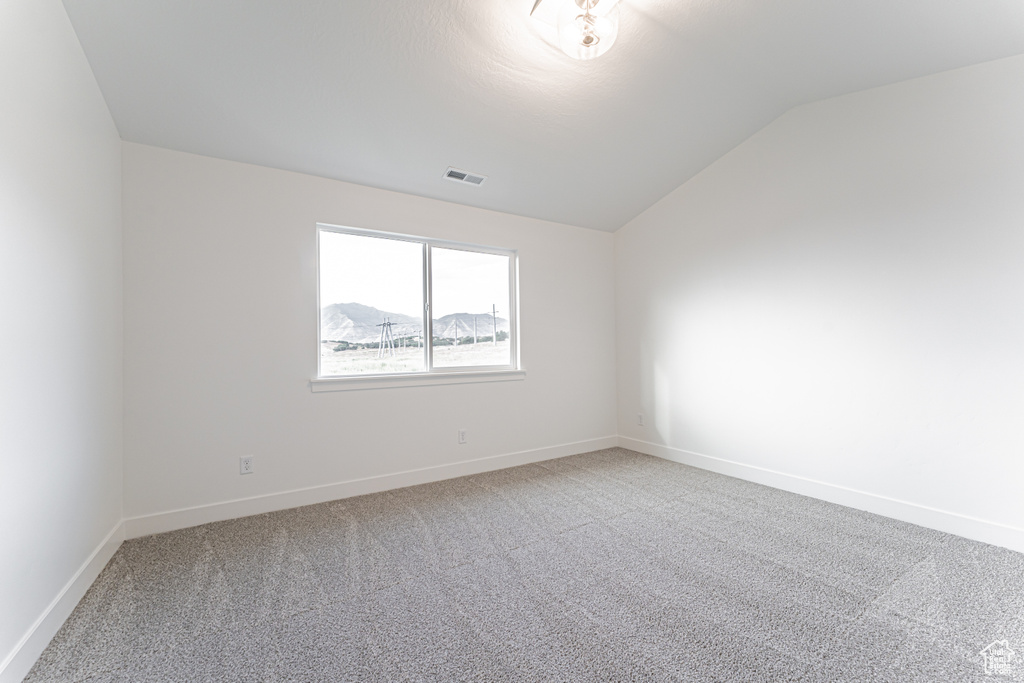 Unfurnished room with vaulted ceiling and light carpet