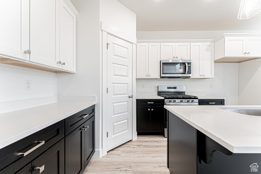 Kitchen featuring stainless steel appliances, white cabinets, and dark cabinets