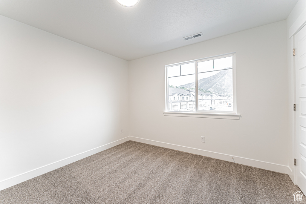 Carpeted spare room featuring baseboards
