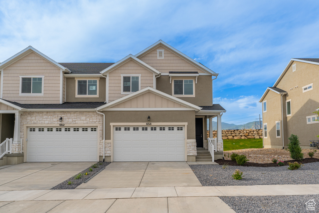 View of front of house with stone siding, board and batten siding, a garage, and driveway
