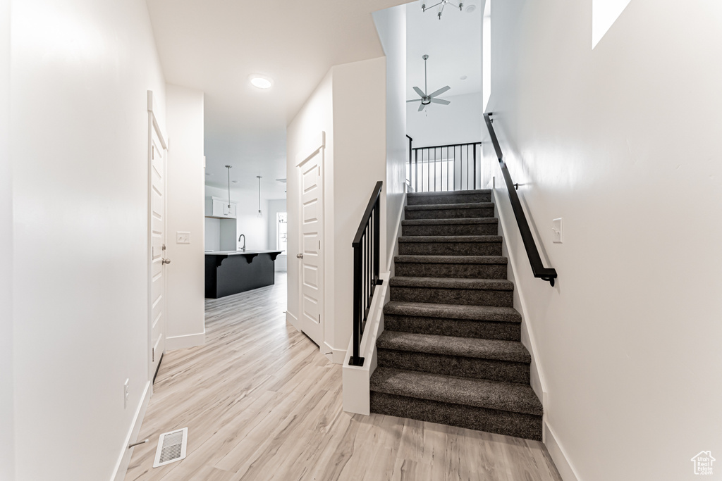 Staircase with a ceiling fan and wood finished floors