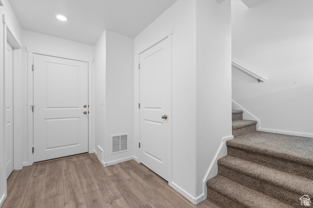 Interior space with wood finished floors, visible vents, baseboards, recessed lighting, and stairs
