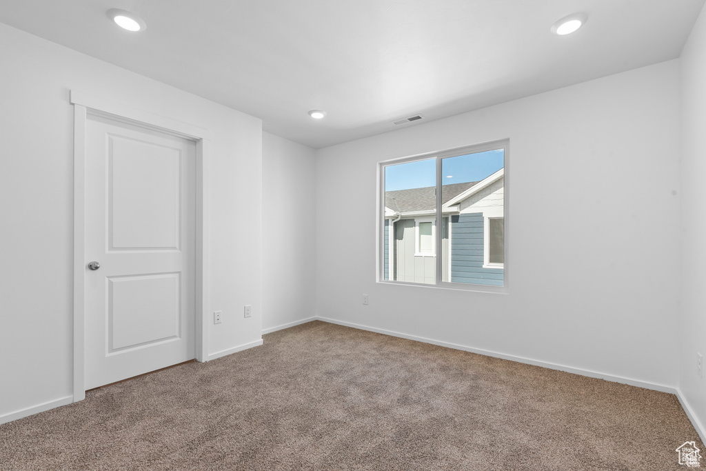 Carpeted empty room with visible vents, recessed lighting, and baseboards