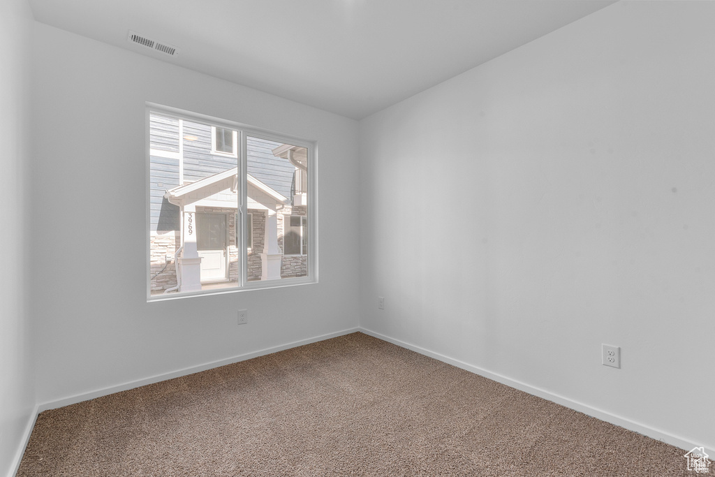 Carpeted empty room with visible vents and baseboards