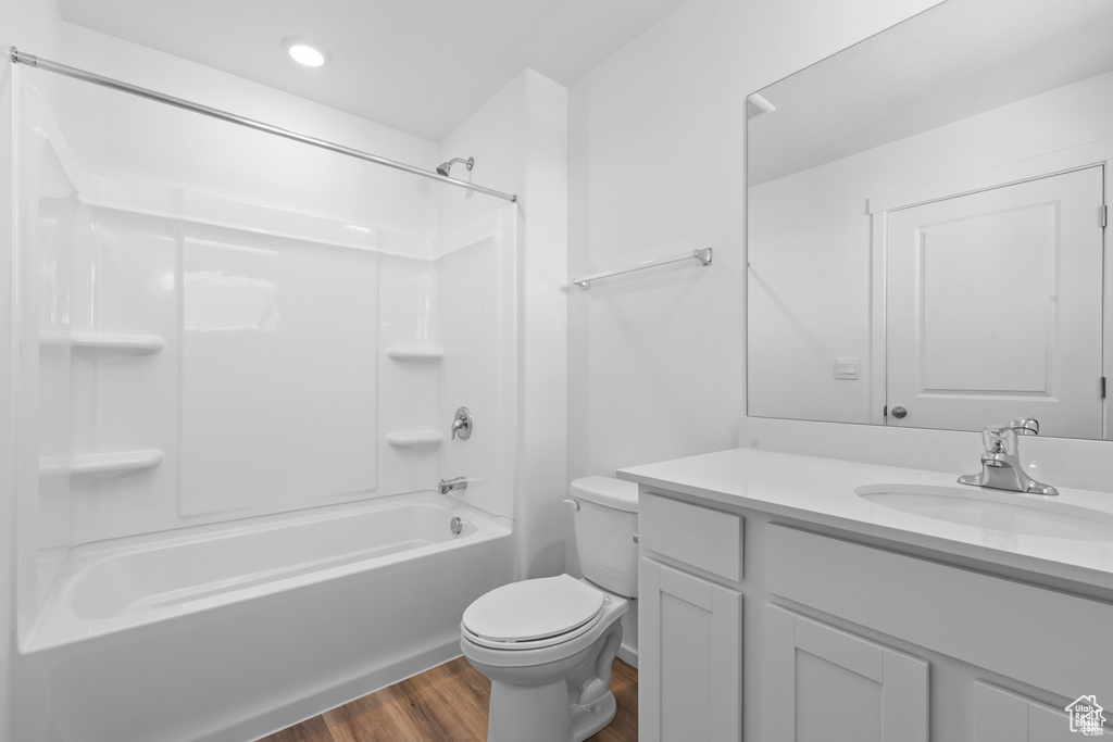 Bathroom featuring toilet, vanity, recessed lighting, wood finished floors, and washtub / shower combination