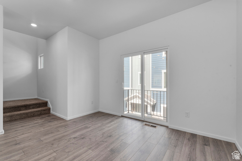 Spare room with stairway, wood finished floors, visible vents, and baseboards