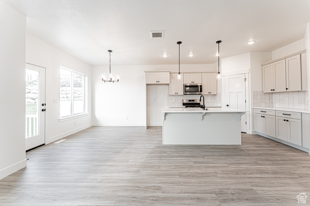 Kitchen with stainless steel appliances, tasteful backsplash, a chandelier, light countertops, and recessed lighting
