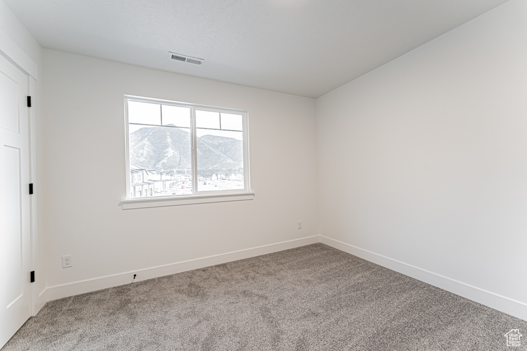 Carpeted empty room featuring baseboards and a mountain view