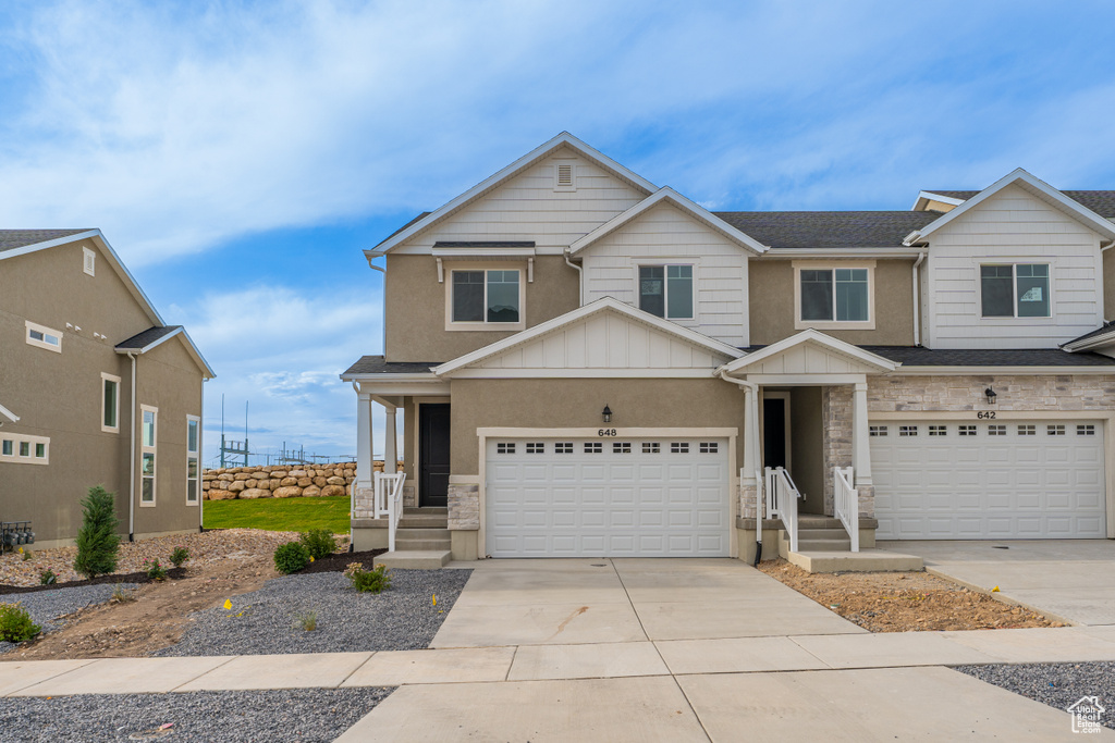 View of front of home featuring an attached garage, board and batten siding, stone siding, and concrete driveway