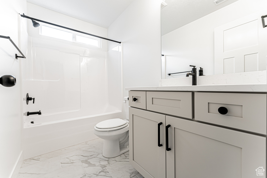Full bathroom with marble look tiles, vanity, and shower / tub combination