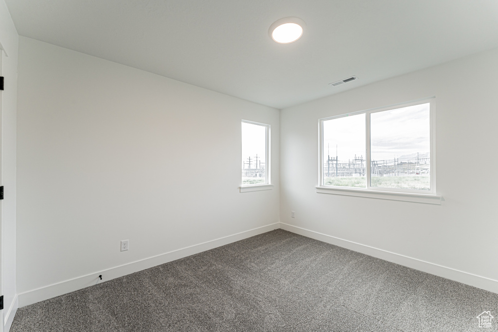 Spare room with dark colored carpet and baseboards
