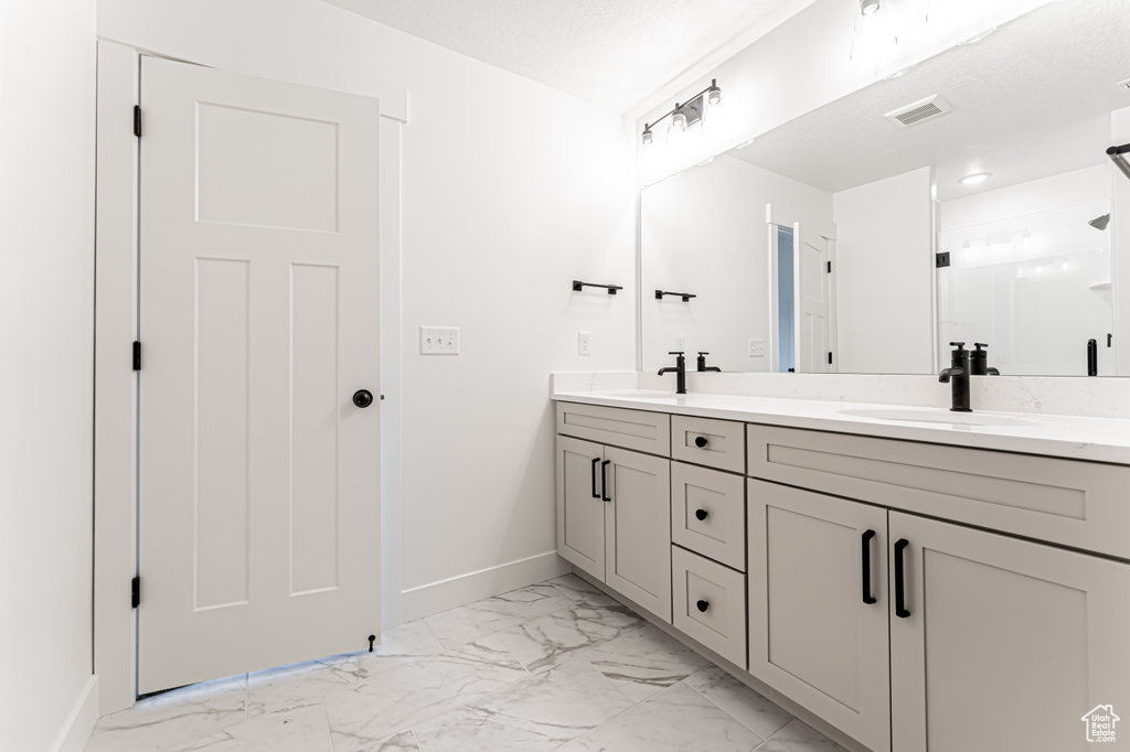 Full bath featuring marble finish floors, double vanity, and an enclosed shower
