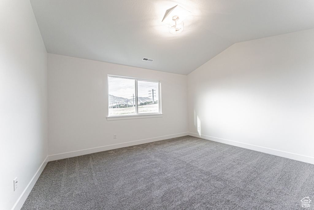 Spare room with carpet flooring and lofted ceiling