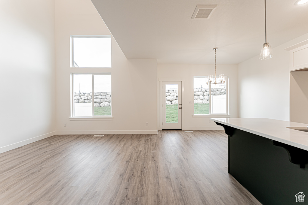 Unfurnished dining area with healthy amount of natural light, light wood-style flooring, and a chandelier
