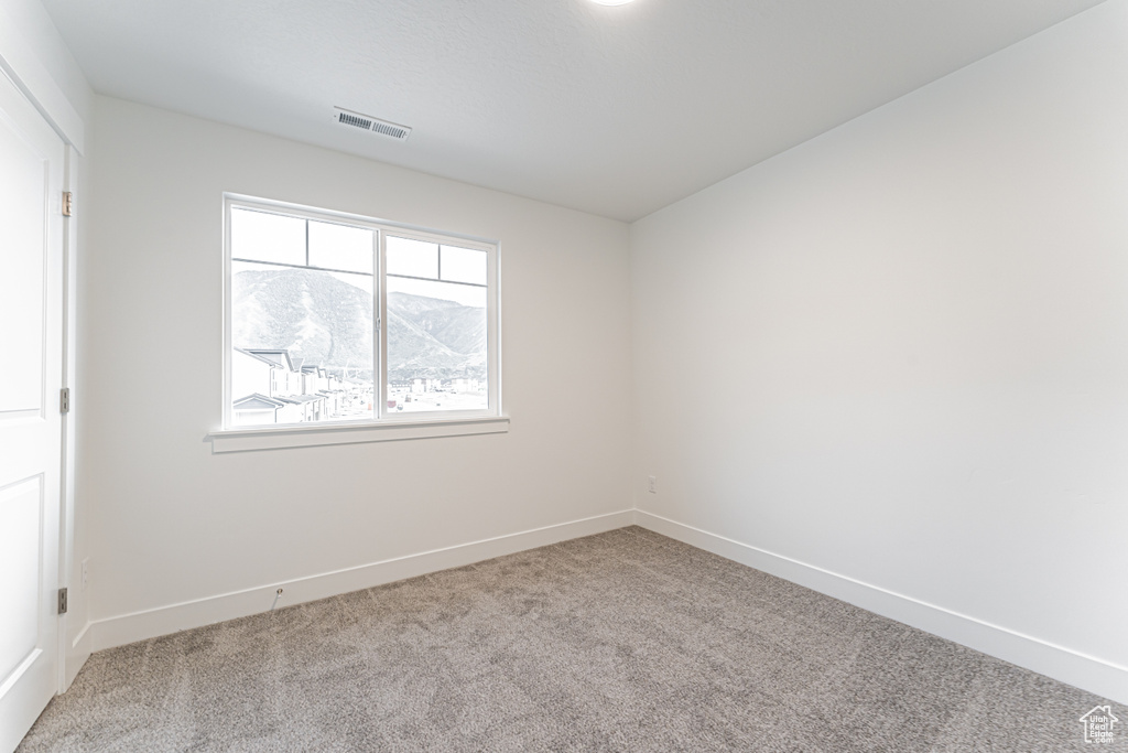 Carpeted empty room featuring baseboards and a mountain view