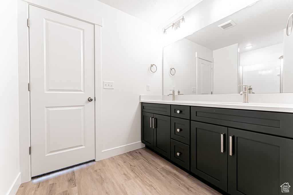 Full bathroom with double vanity and wood finished floors